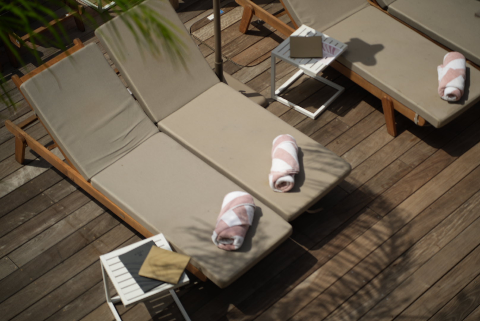 Sunbeds with rolled towels on a wooden deck seen from above