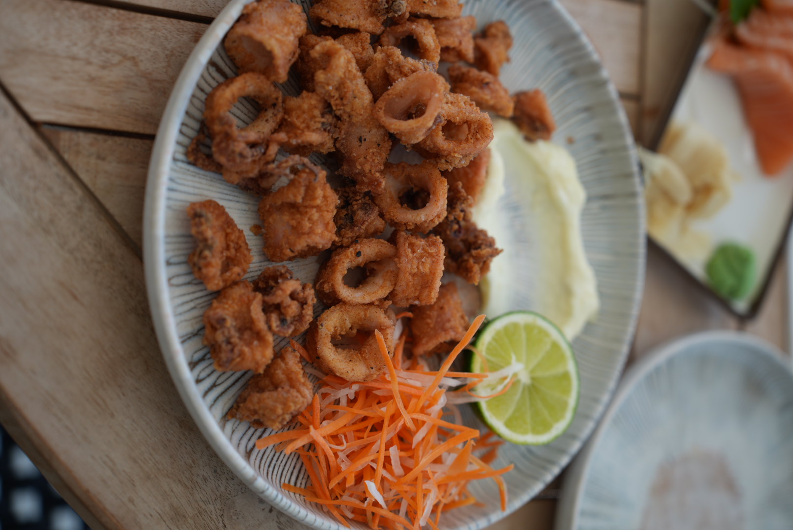 Plate of fried calamari with lime and shredded carrot