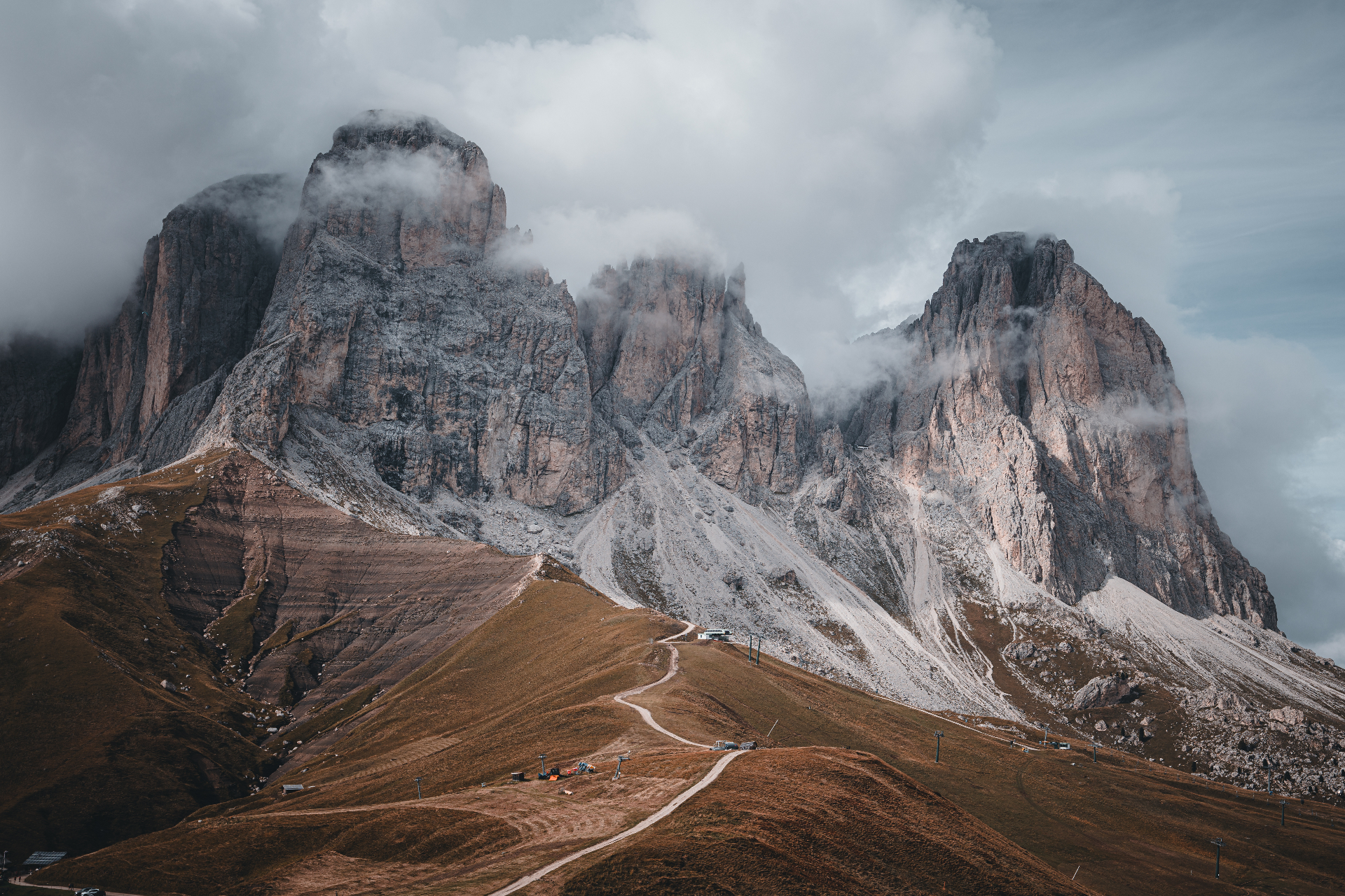 Dolomite peaks wrapped in clouds above golden pastures
